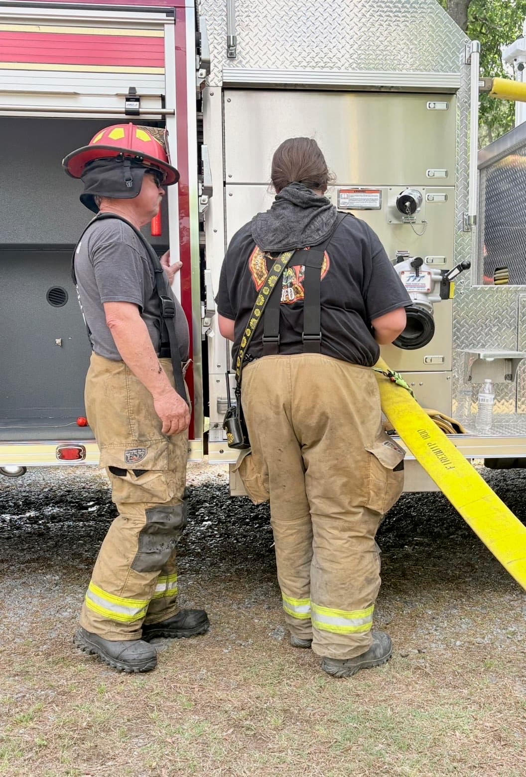 Youth firefighter training beside a fire engine pump panel